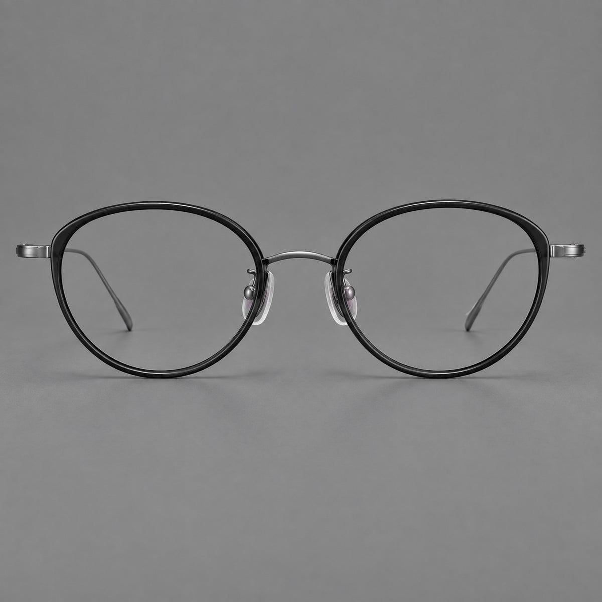Round eyeglasses in acetate and titanium with a slim curved bridge and fine metal temples in Glossy Black / Gunmetal, front view