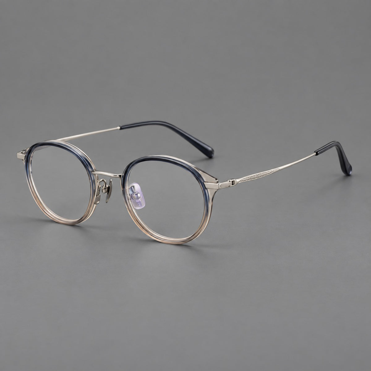 Retro panto eyeglasses in acetate and titanium with an arched bridge and engraved metal temples in Grey Blue Tea Gradient / Light Gunmetal, three quarter view