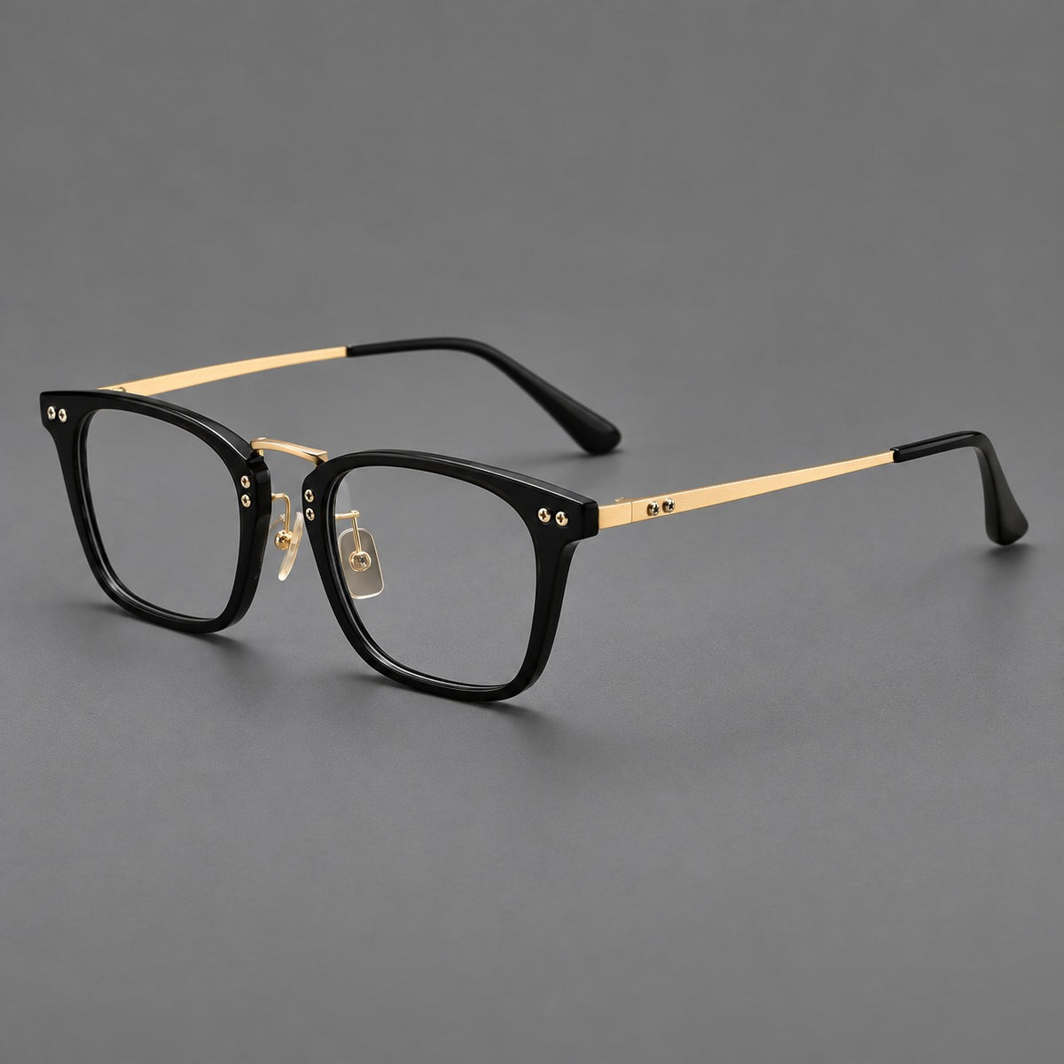 Acetate and titanium eyeglasses with angular rectangular rims and a curved metal bridge in Black / Gold, three quarter view