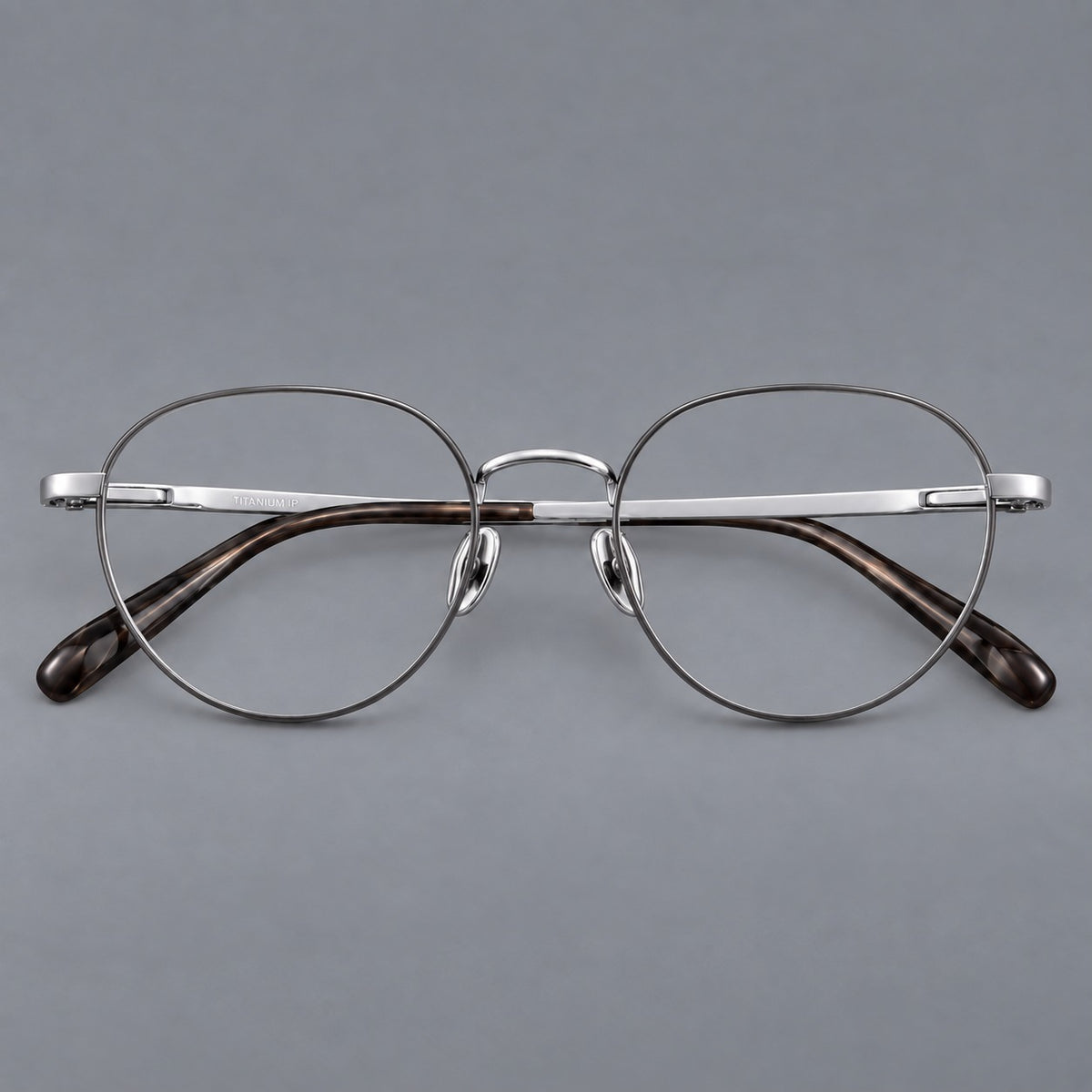 Classic round titanium glasses with broad flat temples and inset hinge details in Grey and Silver, front view