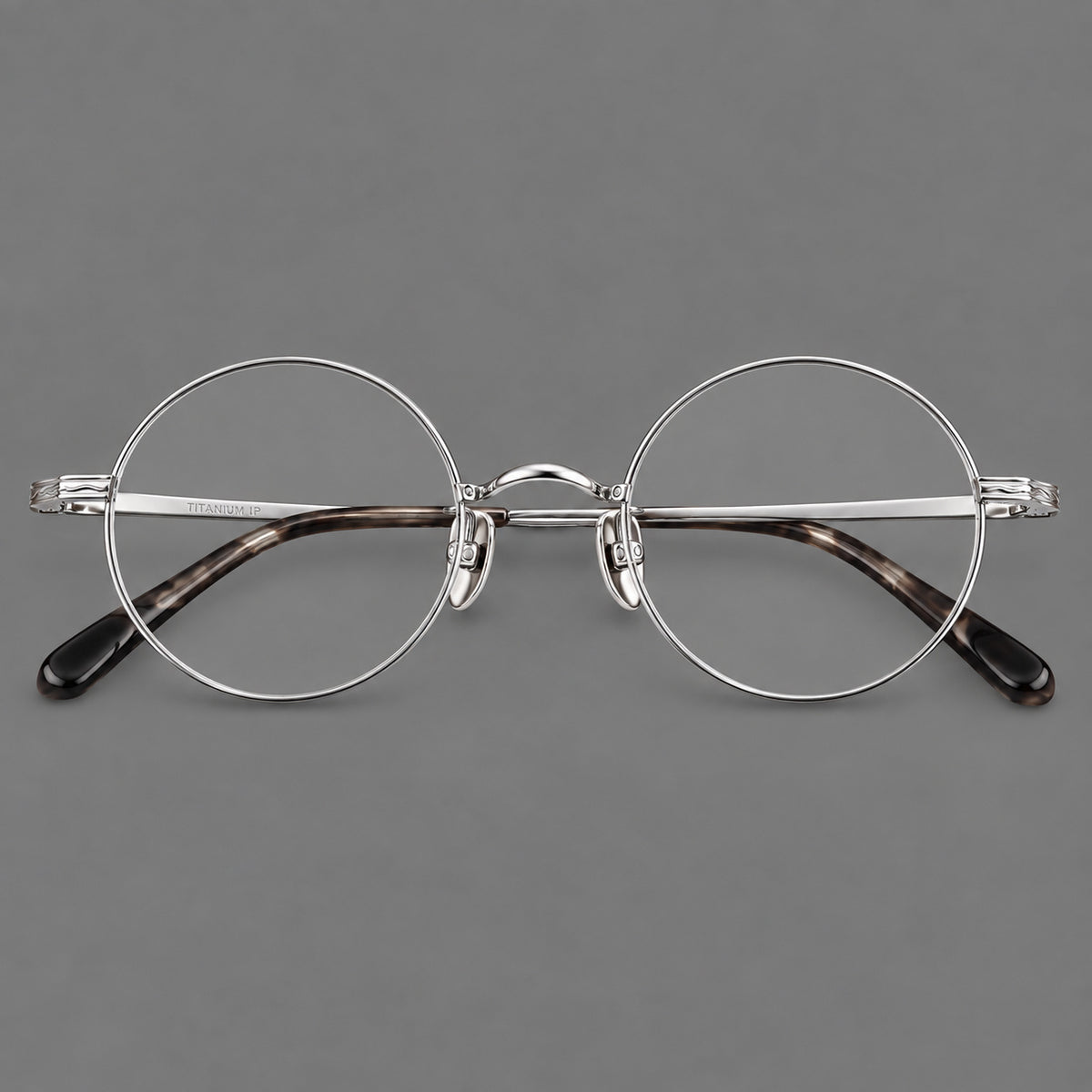 Compact circular titanium glasses with a curved bridge and wavy engraved temples in Silver, front view