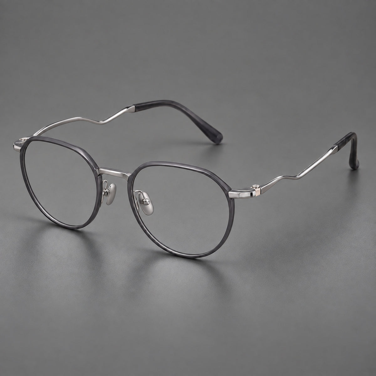 Rounded titanium glasses with a short bridge and distinctive wavy metal temples in Matte Grey and Silver, three quarter view
