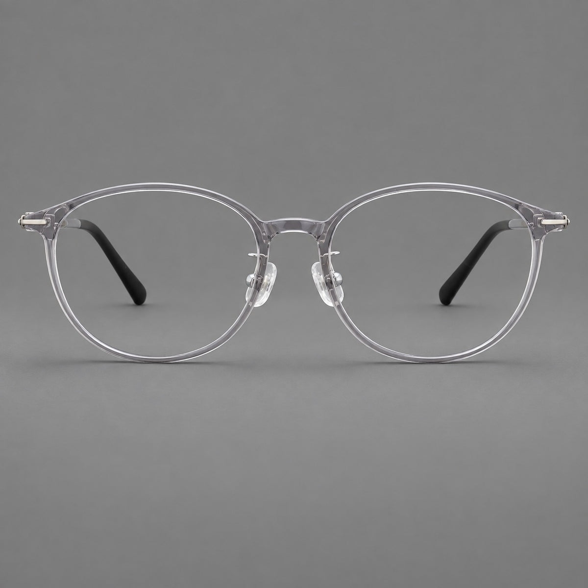 Slim oval plastic eyeglasses with a low profile and subtle metal corner accents in Clear Grey, front view