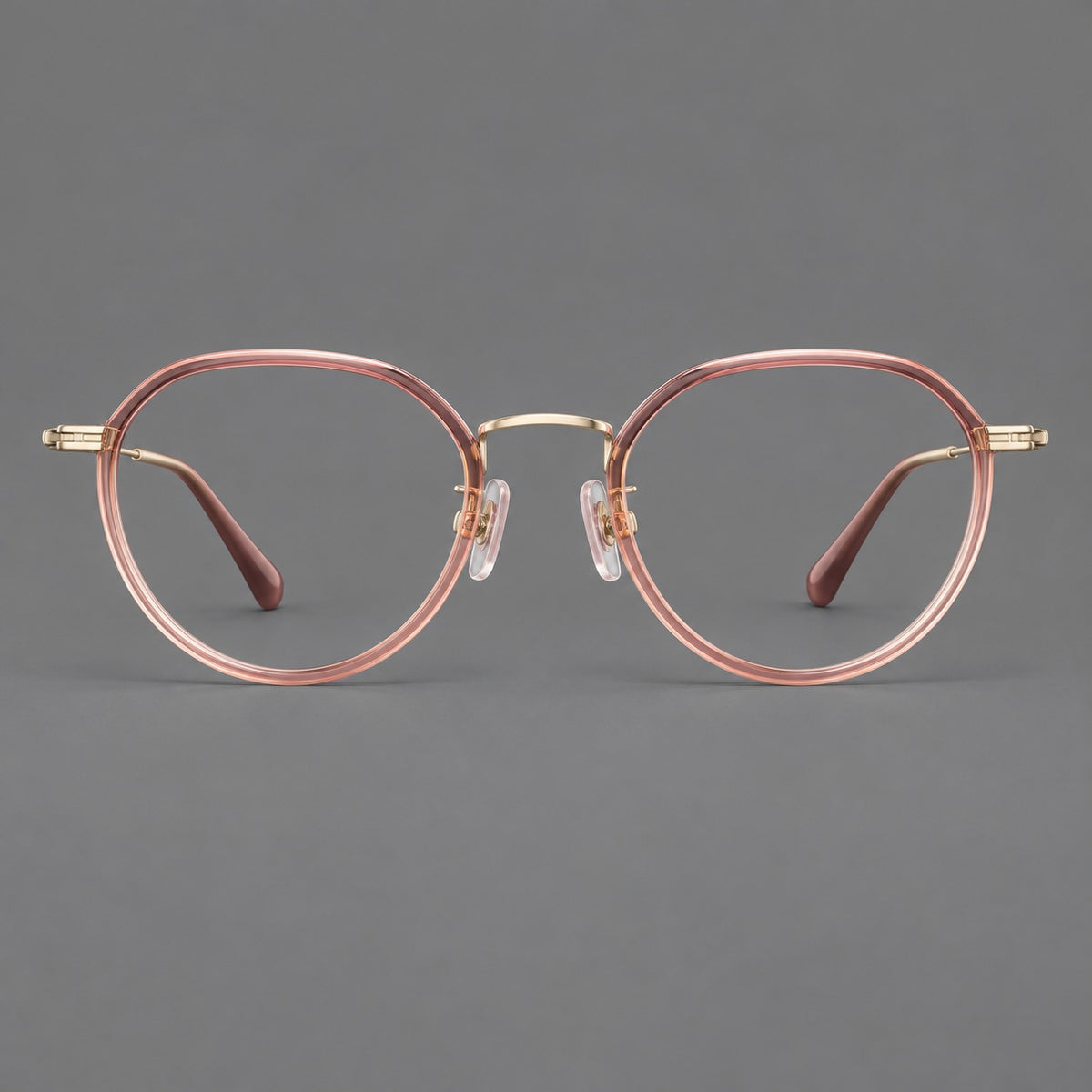 Rounded eyeglasses in acetate and titanium with gently arched brows and engraved metal temples in Amber Pink / Gold, front view