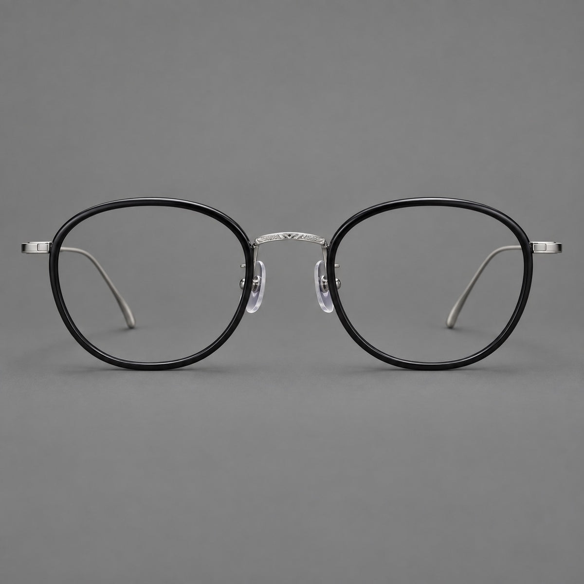 Vintage round eyeglasses in acetate and titanium with an engraved bridge and slender temples in Glossy Black / Gunmetal, front view