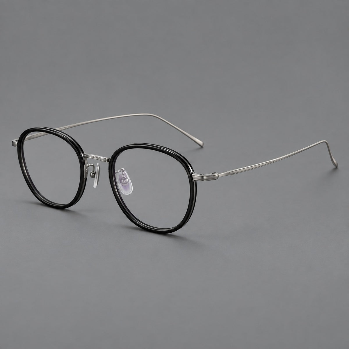 Vintage round eyeglasses in acetate and titanium with an engraved bridge and slender temples in Glossy Black / Gunmetal, three quarter view
