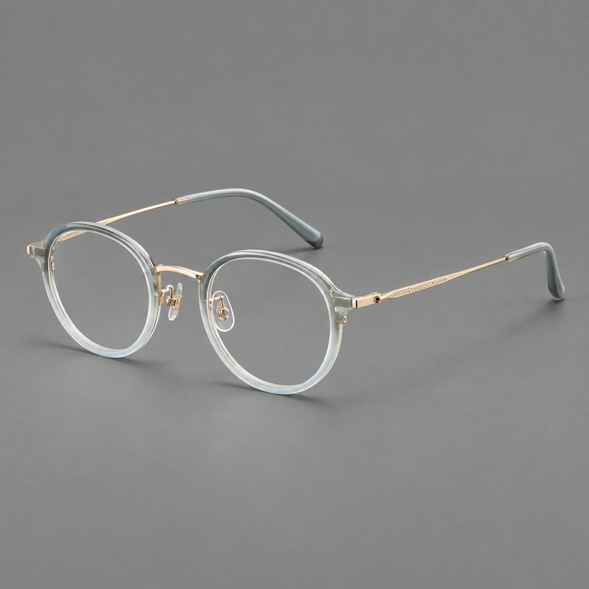 Softly rounded eyeglasses in acetate and titanium with a curved bridge and engraved temples in Ice Blue Grey / Gold, three quarter view