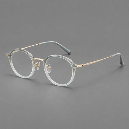 Softly rounded eyeglasses in acetate and titanium with a curved bridge and engraved temples in Ice Blue Grey / Gold, three quarter view