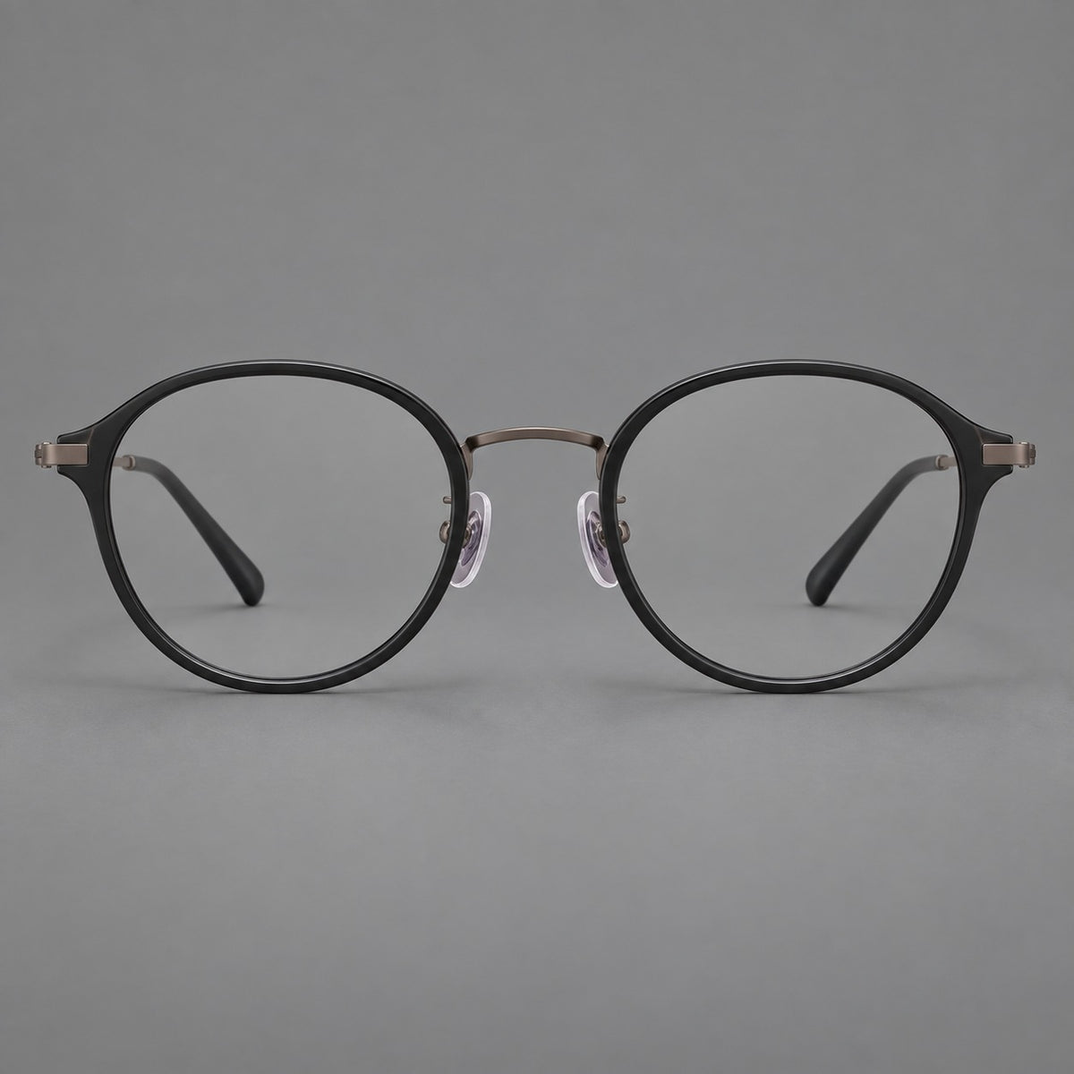 Softly rounded eyeglasses in acetate and titanium with a curved bridge and engraved temples in Matte Black / Antique Copper, front view
