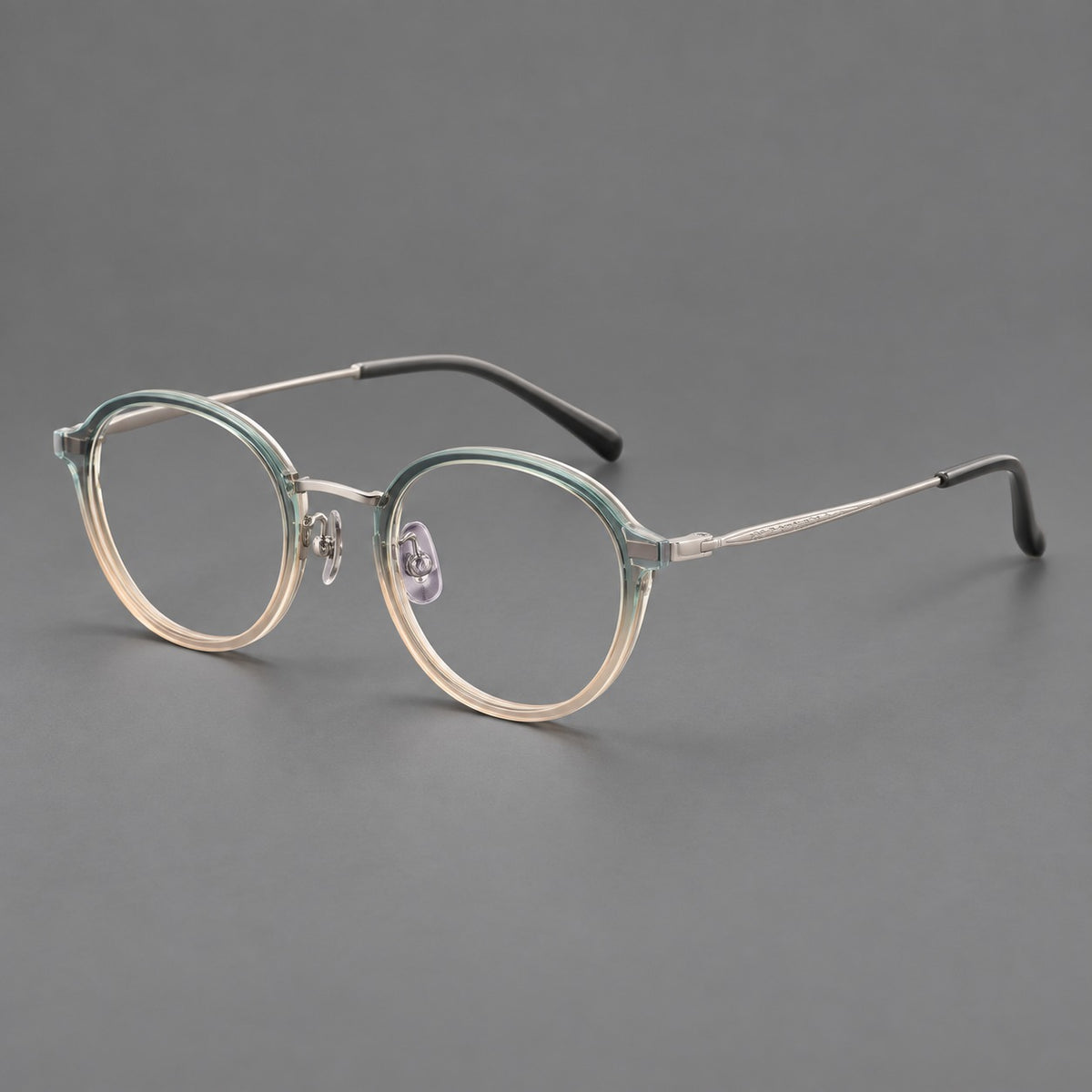 Softly rounded eyeglasses in acetate and titanium with a curved bridge and engraved temples in Green Tea Gradient / Silver, three quarter view