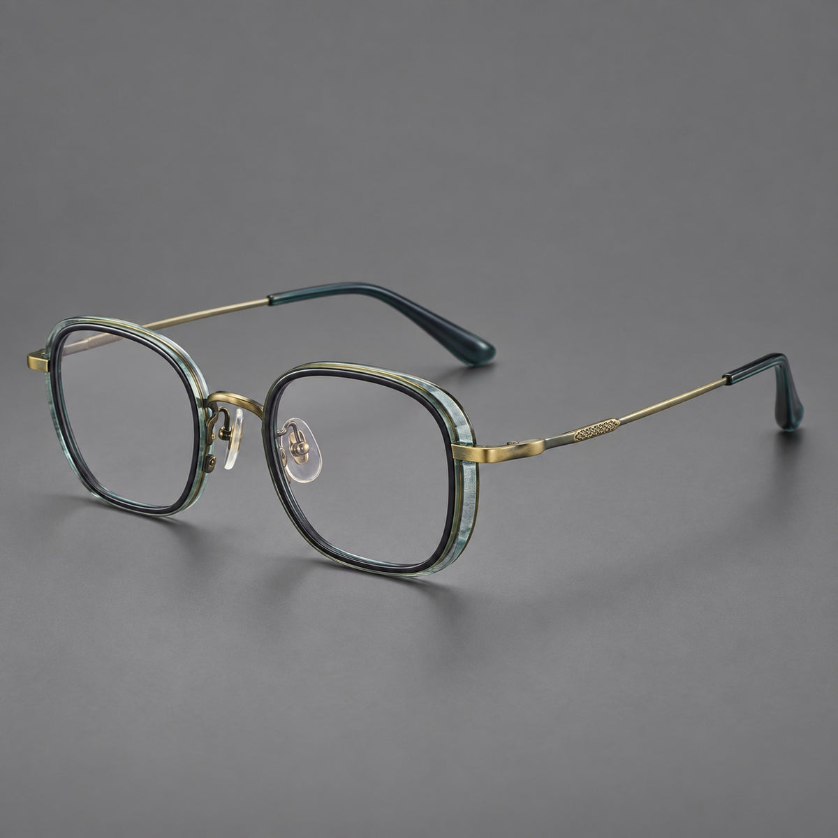 Rounded square eyeglasses in acetate and titanium with an arched bridge and engraved temples in Misted Clear Green / Antique Gold, three quarter view