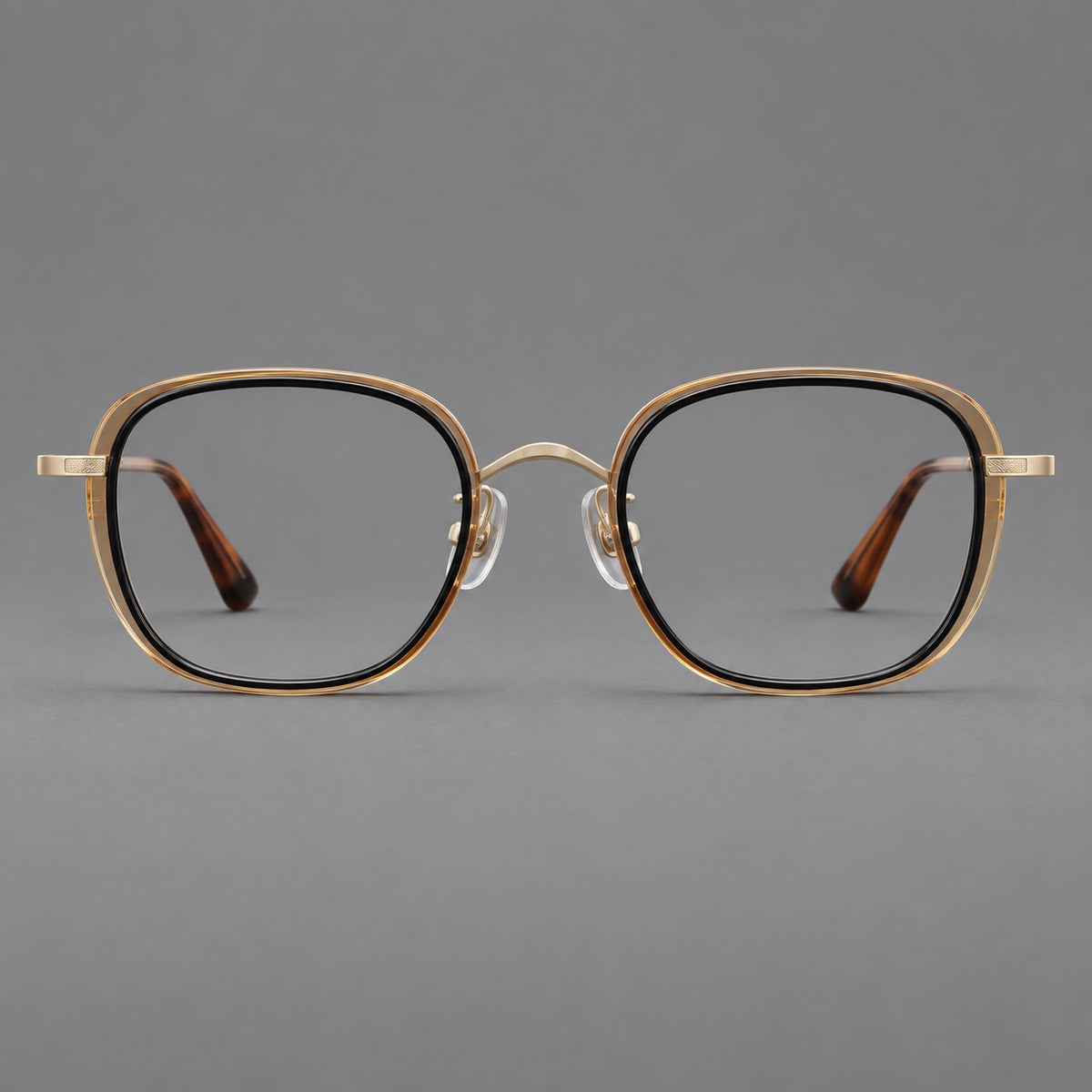 Rounded square eyeglasses in acetate and titanium with an arched bridge and engraved temples in Black and Clear Tea / Light Gold, front view