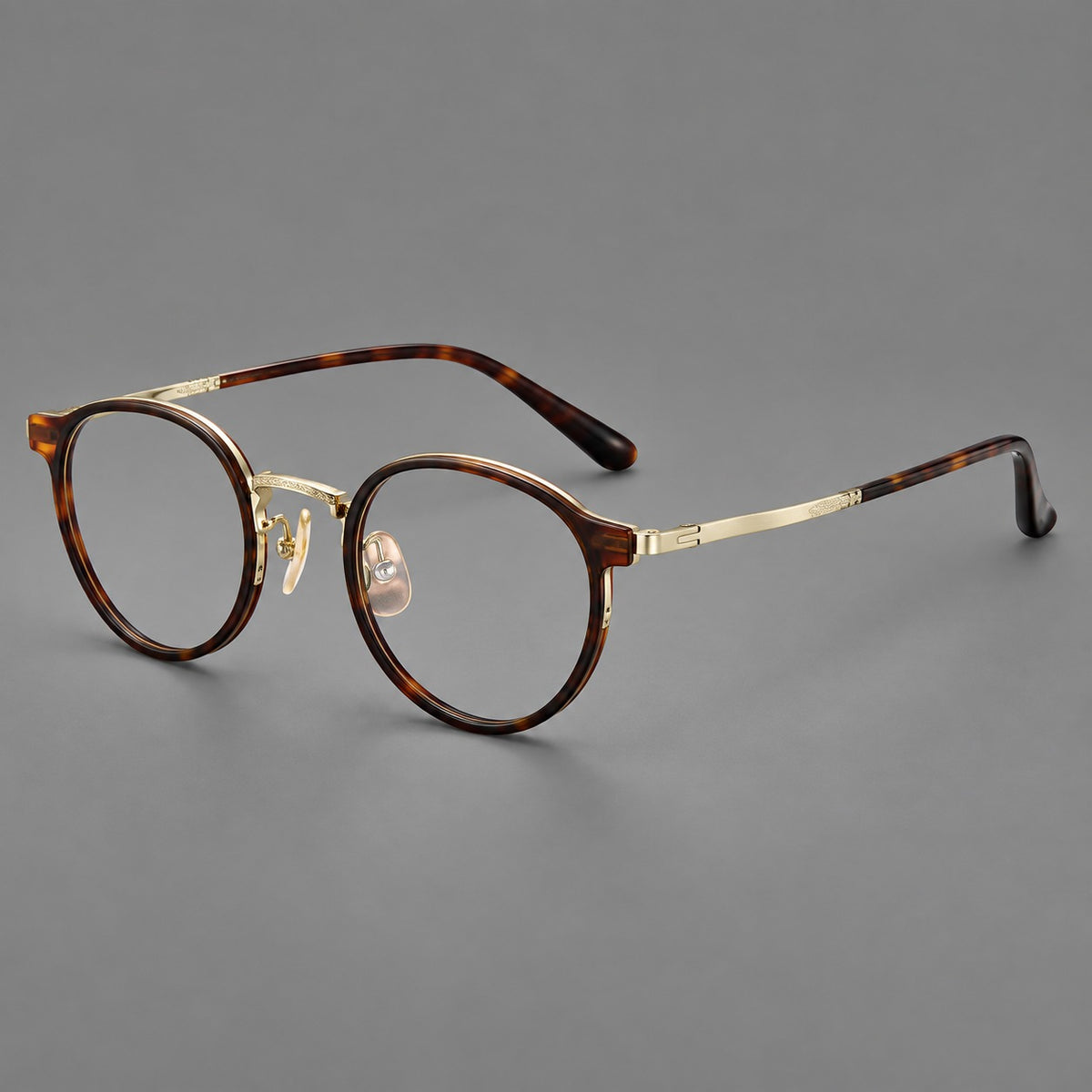 Round eyeglasses in acetate and titanium with widened outer corners and slender metal temples in Tortoiseshell / Gold, three quarter view