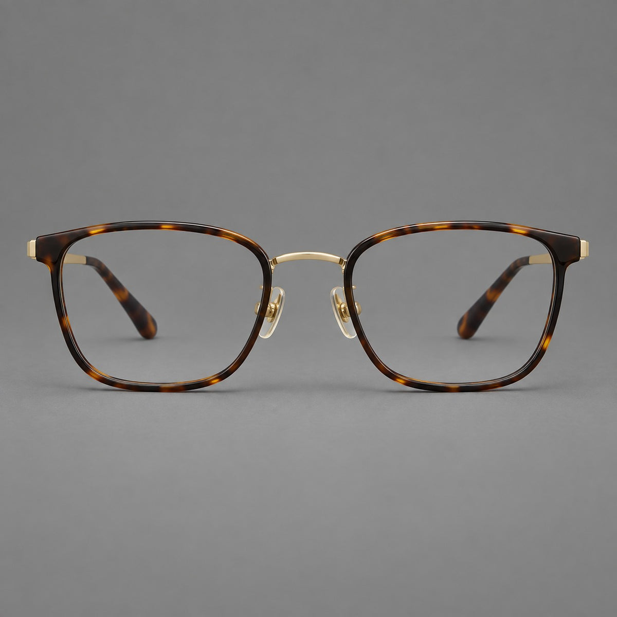 Rounded rectangular eyeglasses in acetate and titanium with bold corners and engraved metal temples in Tortoiseshell / Gold, front view