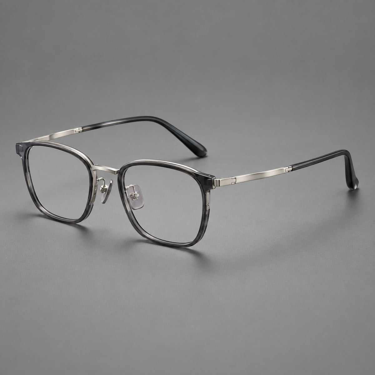 Rounded rectangular eyeglasses in acetate and titanium with bold corners and engraved metal temples in Clear Grey / Gunmetal, three quarter view
