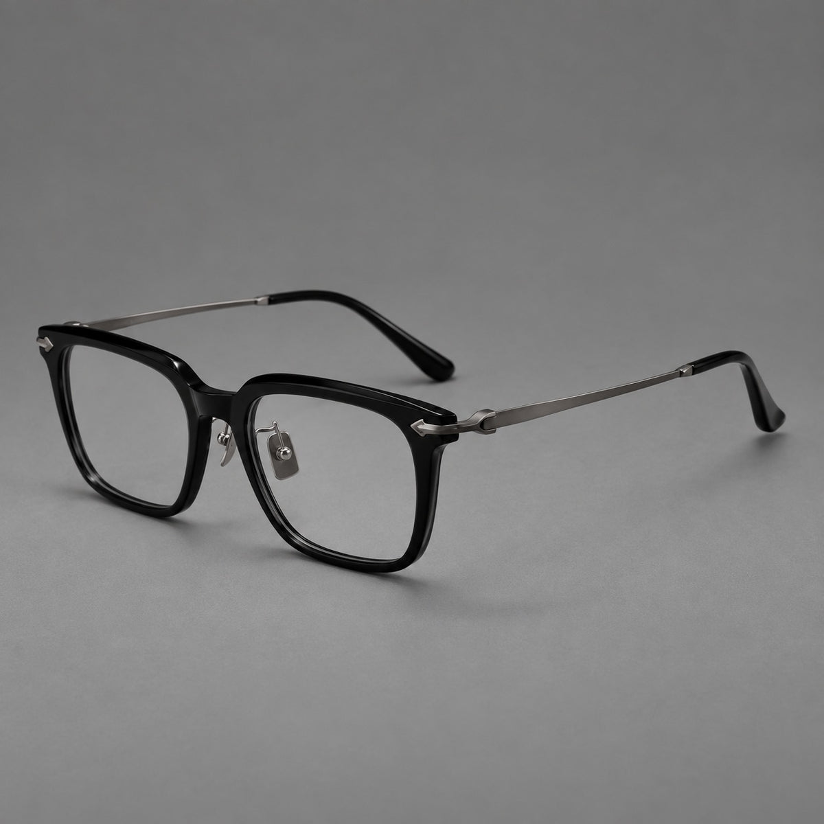 Bold acetate and titanium eyeglasses with rectangular rims and sculpted arrow accents in Black / Gunmetal, three quarter view