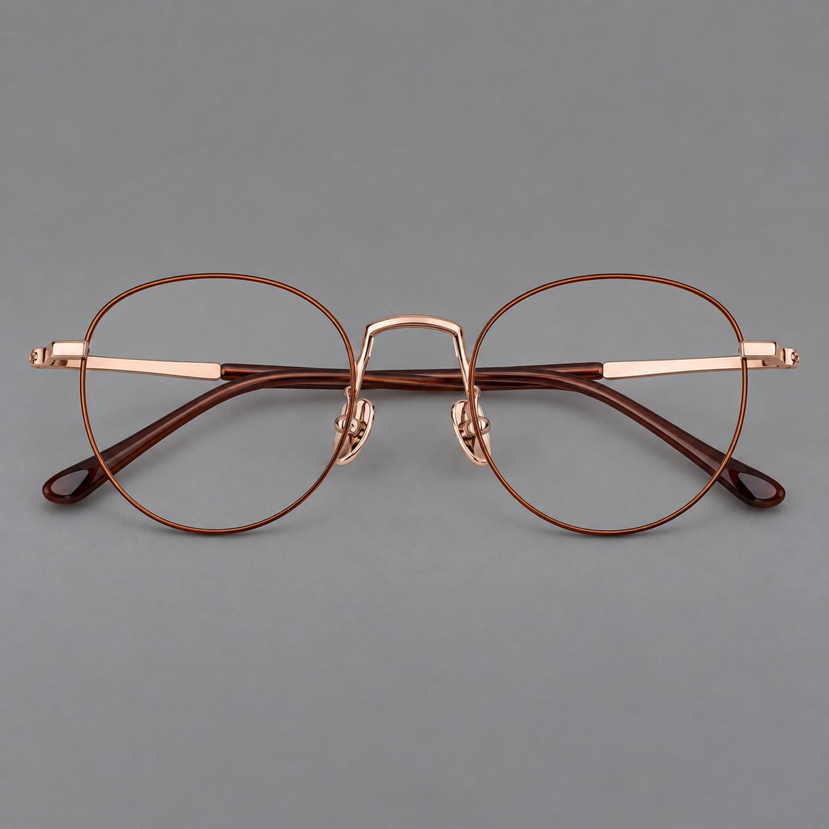 Retro round titanium glasses with a raised bridge and smooth corner shoulders in Brown and Rose Gold, front view