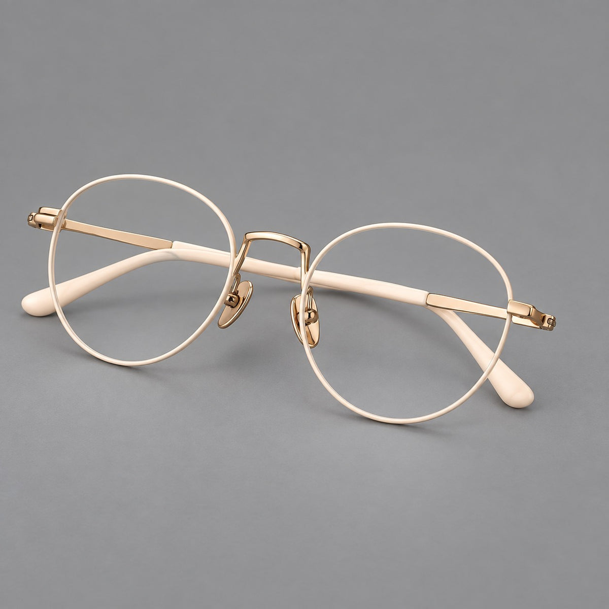 Retro round titanium glasses with a raised bridge and smooth corner shoulders in Cream and Gold, three quarter view