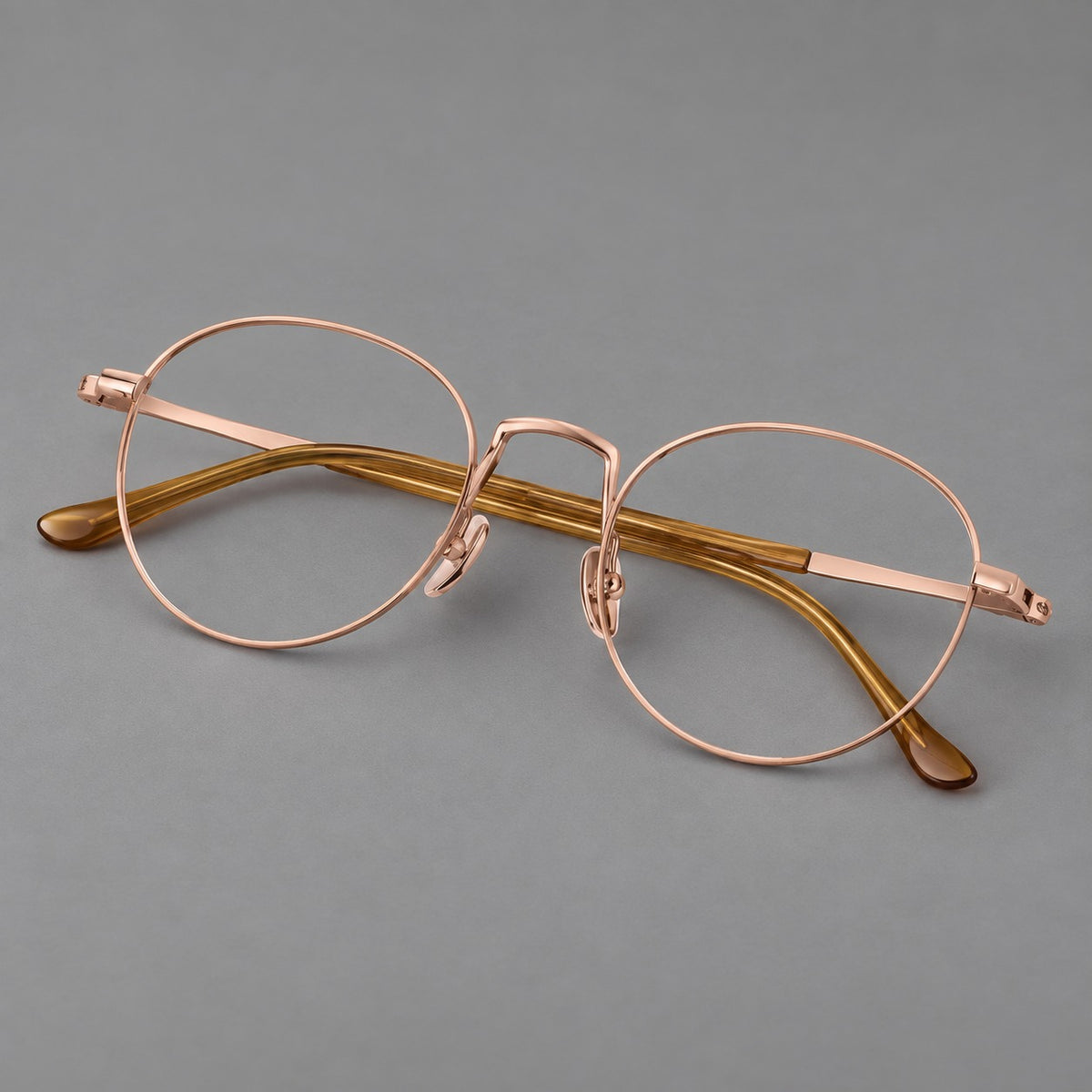 Retro round titanium glasses with a raised bridge and smooth corner shoulders in Rose Gold, three quarter view