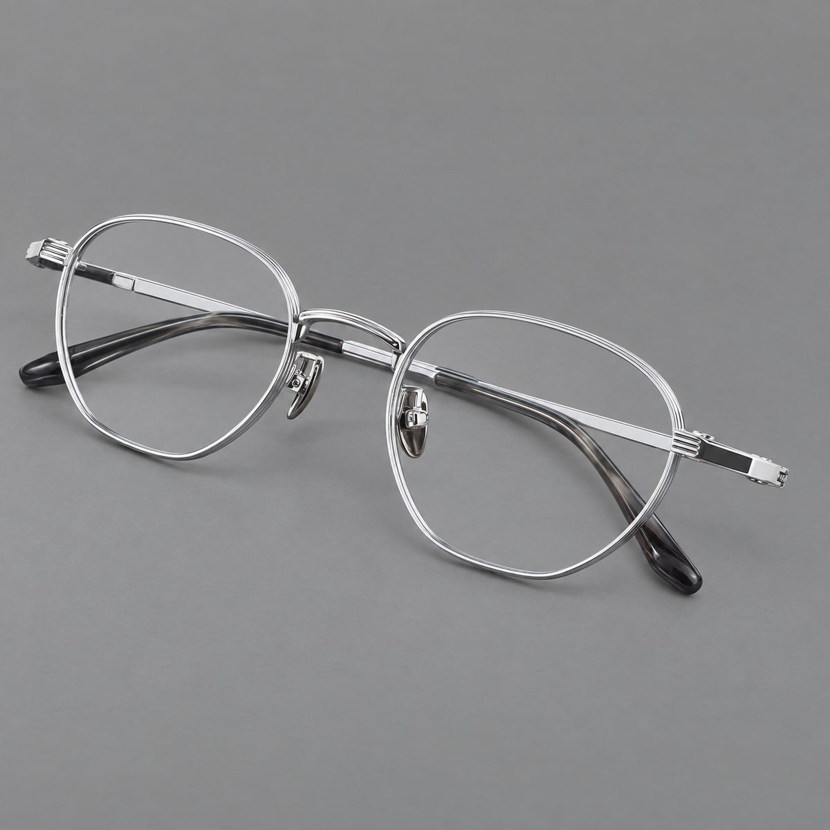 Retro panto titanium glasses with a curved bridge and fine parallel rim grooves in Black and Silver, three quarter view