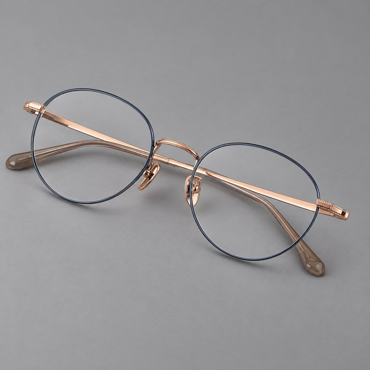 Rounded panto titanium glasses with a raised bridge and dotted temple accents in Blue and Rose Gold, three quarter view