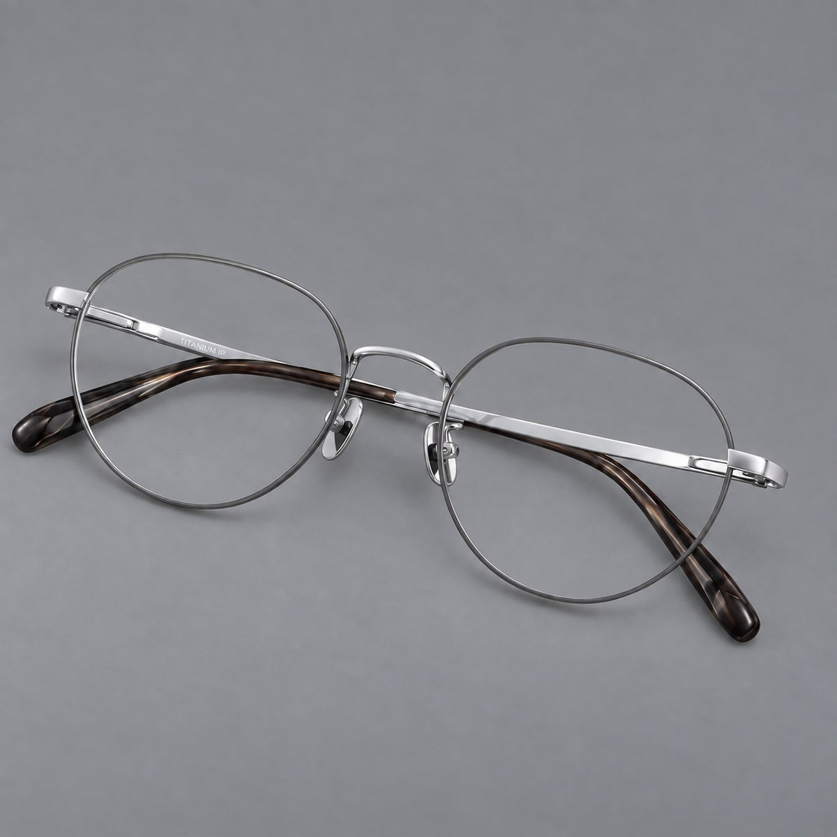 Classic round titanium glasses with broad flat temples and inset hinge details in Grey and Silver, three quarter view