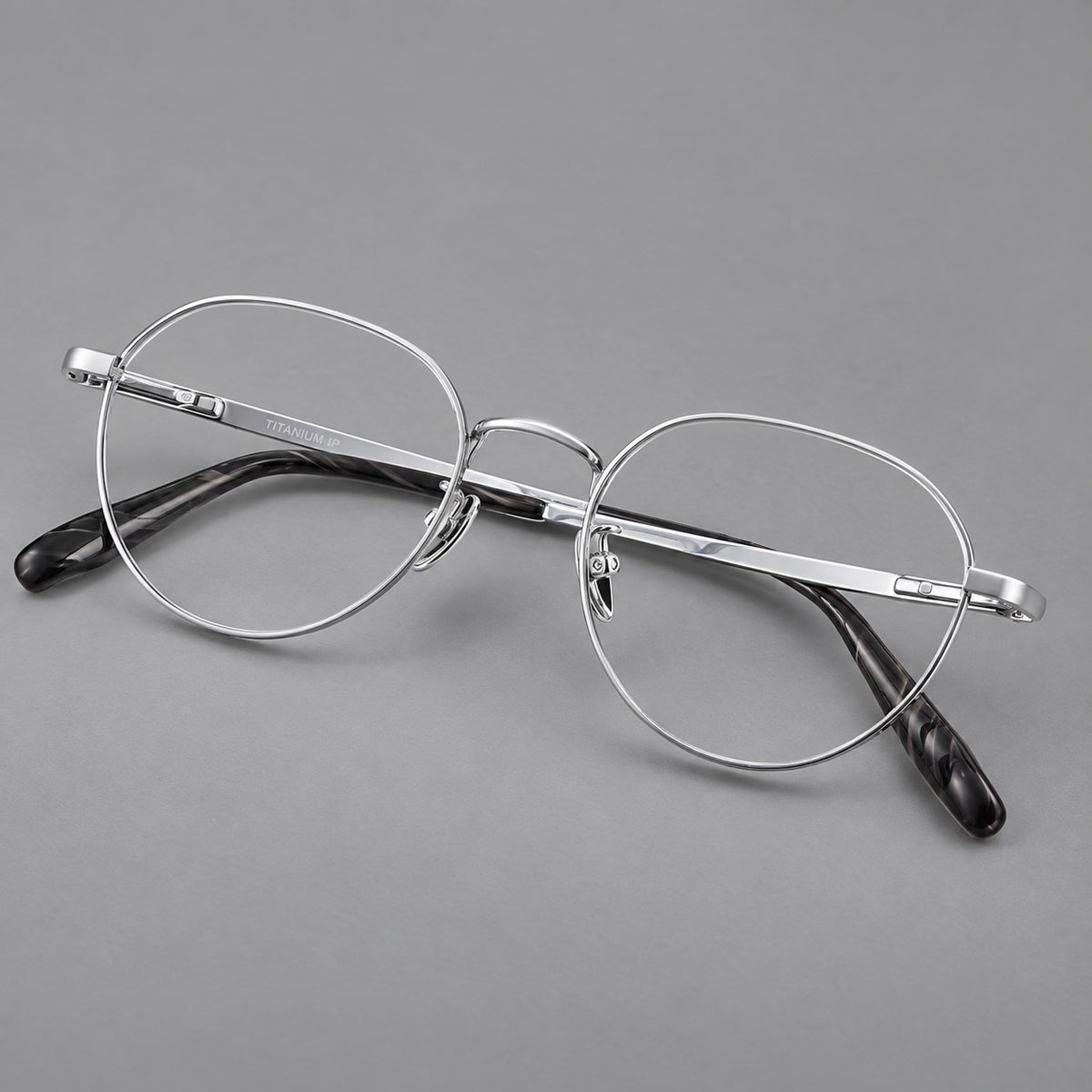 Classic round titanium glasses with broad flat temples and inset hinge details in Silver, three quarter view