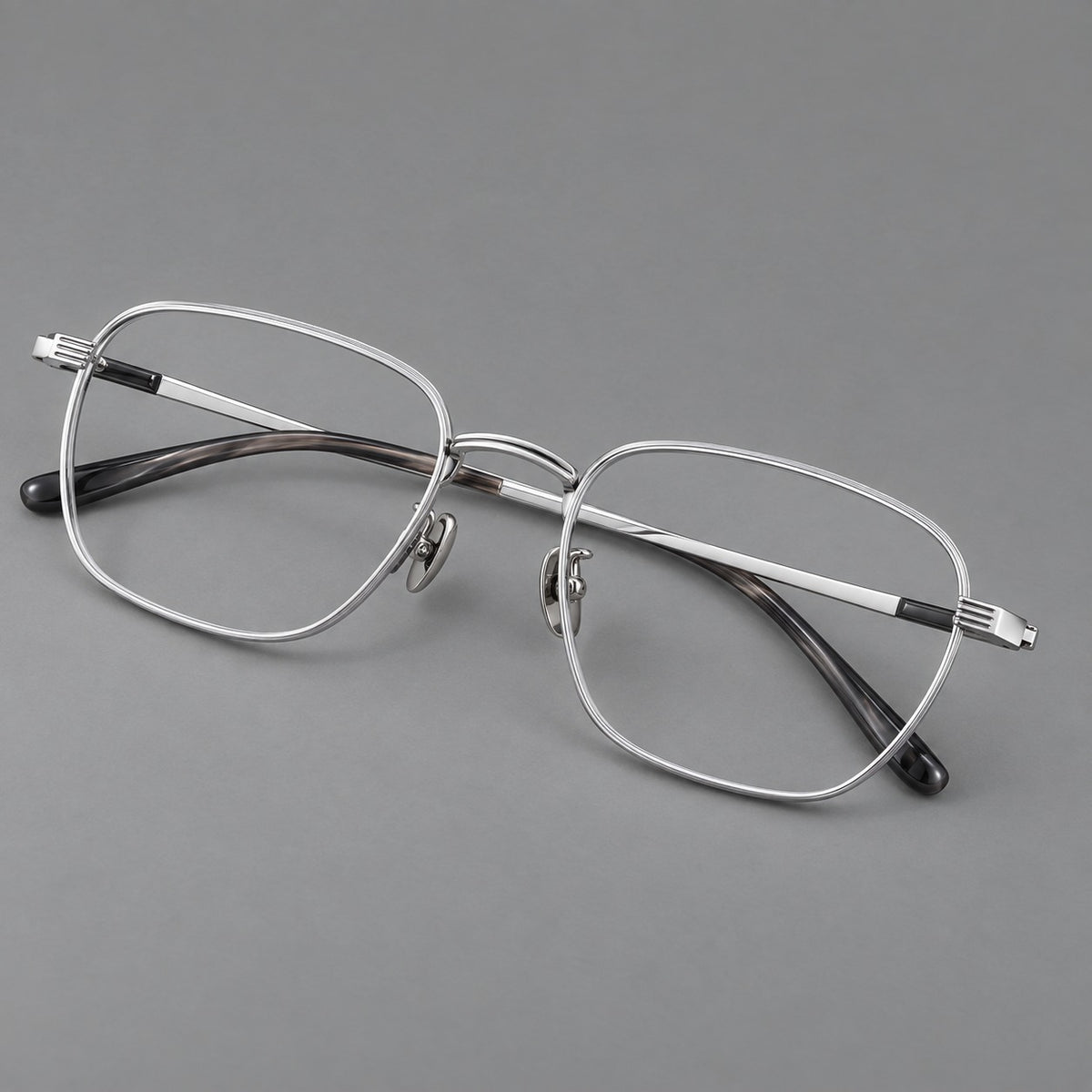 Deep square titanium glasses with a flatter brow and grooved outer shoulders in Black and Silver, three quarter view