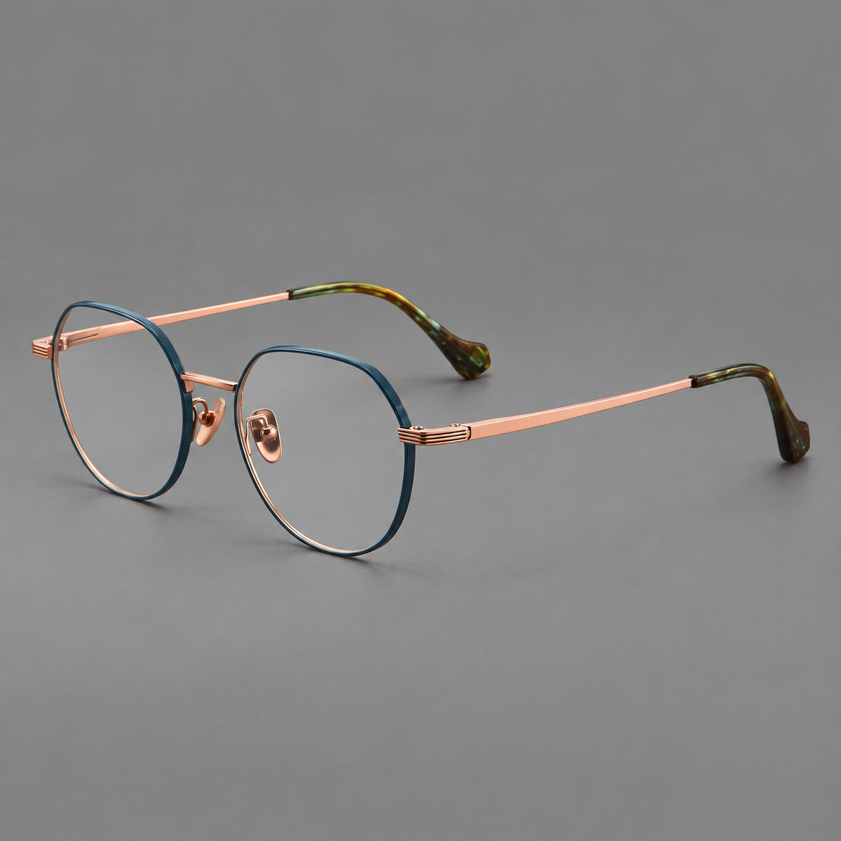 Geometric titanium glasses with soft polygonal rims and fine shoulder detailing in Blue and Rose Gold, three quarter view