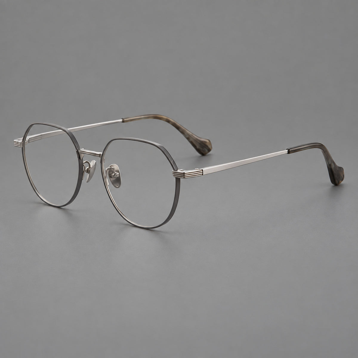 Geometric titanium glasses with soft polygonal rims and fine shoulder detailing in Grey and Silver, three quarter view