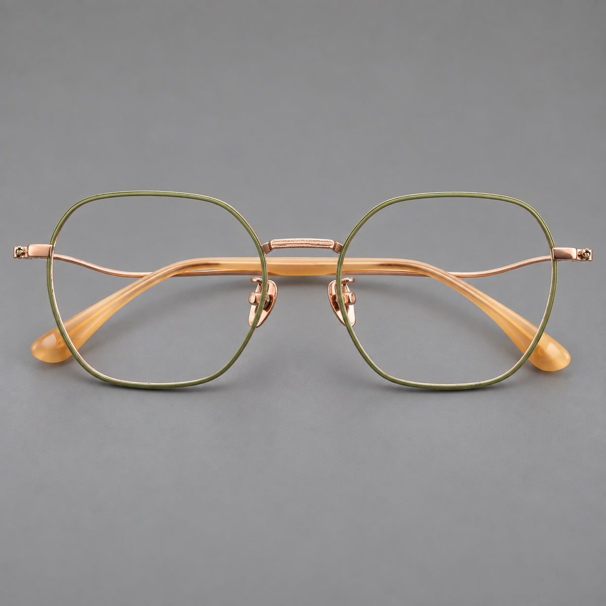 Geometric titanium glasses with engraved rim edges and curved temple joins in Green and Rose Gold, front view