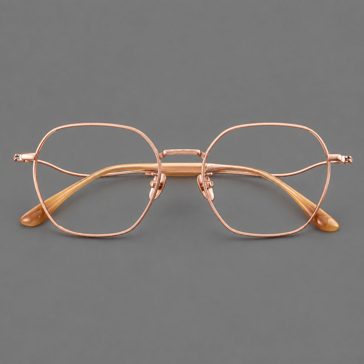 Geometric titanium glasses with engraved rim edges and curved temple joins in Rose Gold, front view
