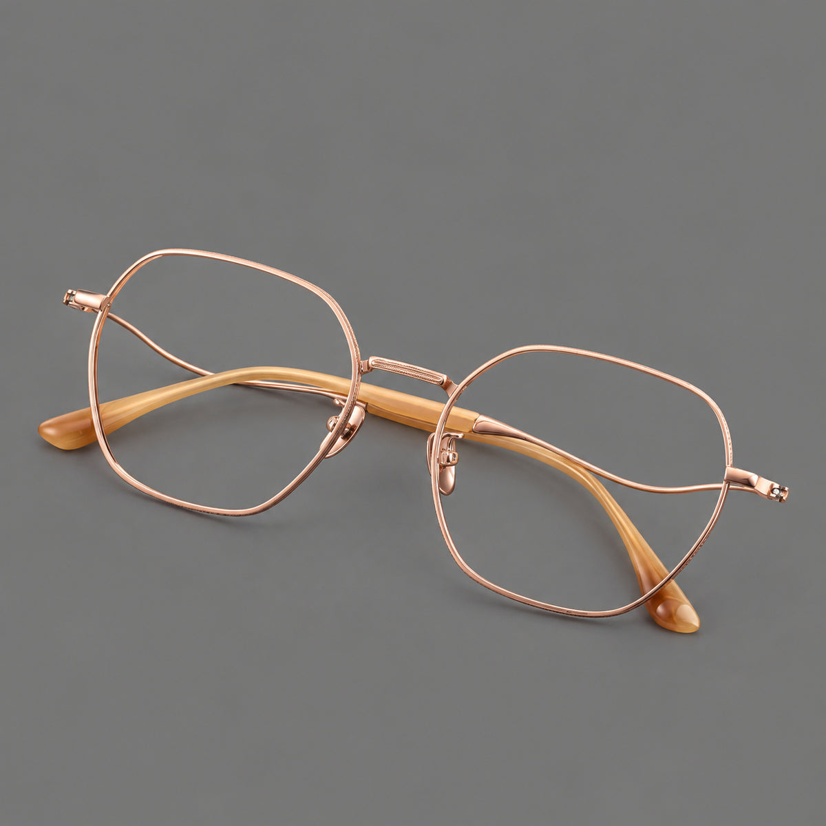 Geometric titanium glasses with engraved rim edges and curved temple joins in Rose Gold, three quarter view