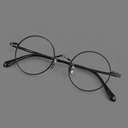 Compact circular titanium glasses with a curved bridge and wavy engraved temples in Black, three quarter view