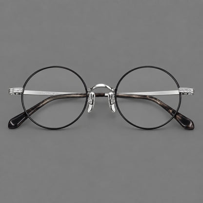 Compact circular titanium glasses with a curved bridge and wavy engraved temples in Black and Silver, front view frame detail