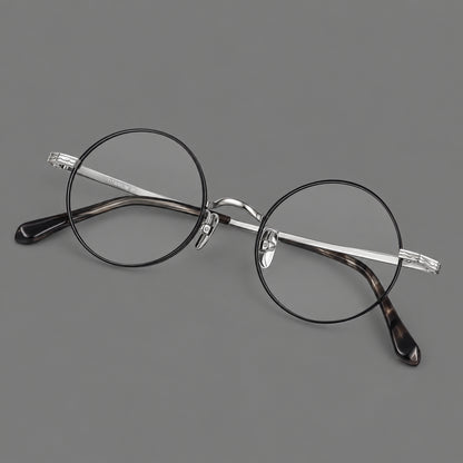 Compact circular titanium glasses with a curved bridge and wavy engraved temples in Black and Silver, three quarter view front view