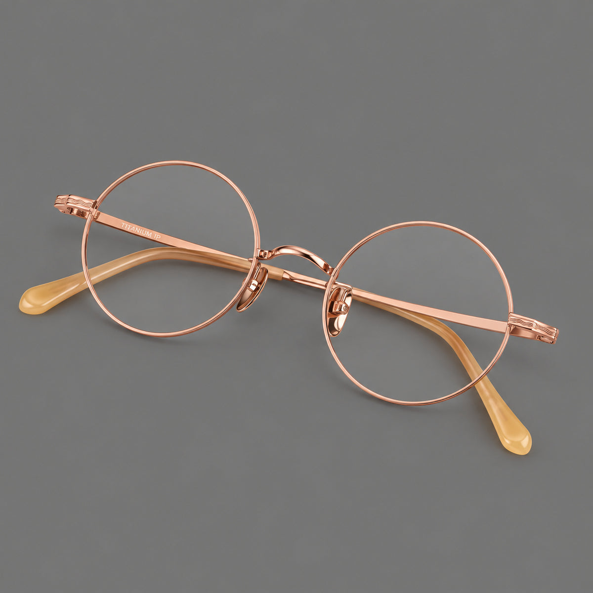 Compact circular titanium glasses with a curved bridge and wavy engraved temples in Rose Gold, three quarter view