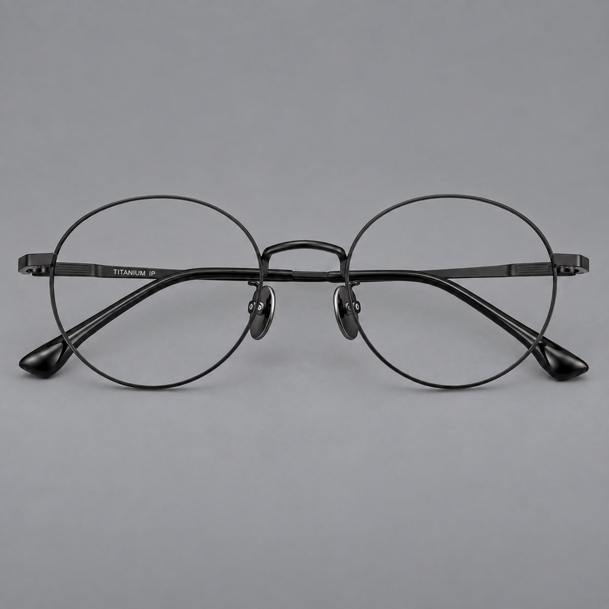 Classic circular titanium glasses with a raised bridge and lined temple accents in Black, front view