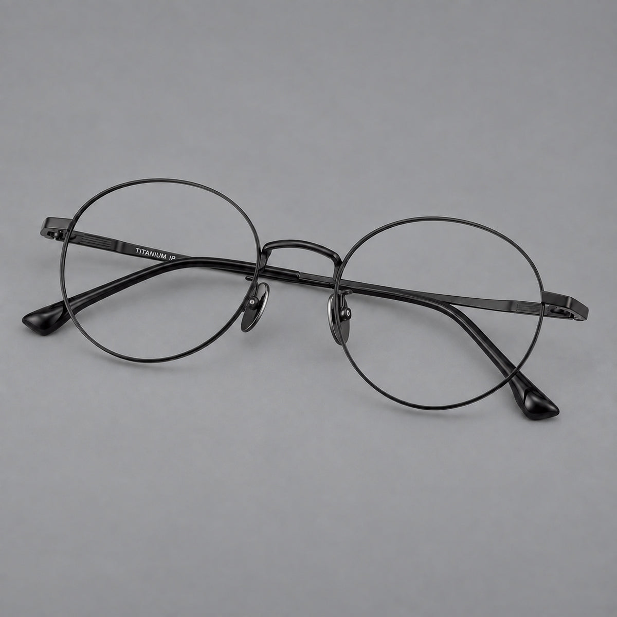 Classic circular titanium glasses with a raised bridge and lined temple accents in Black, three quarter view