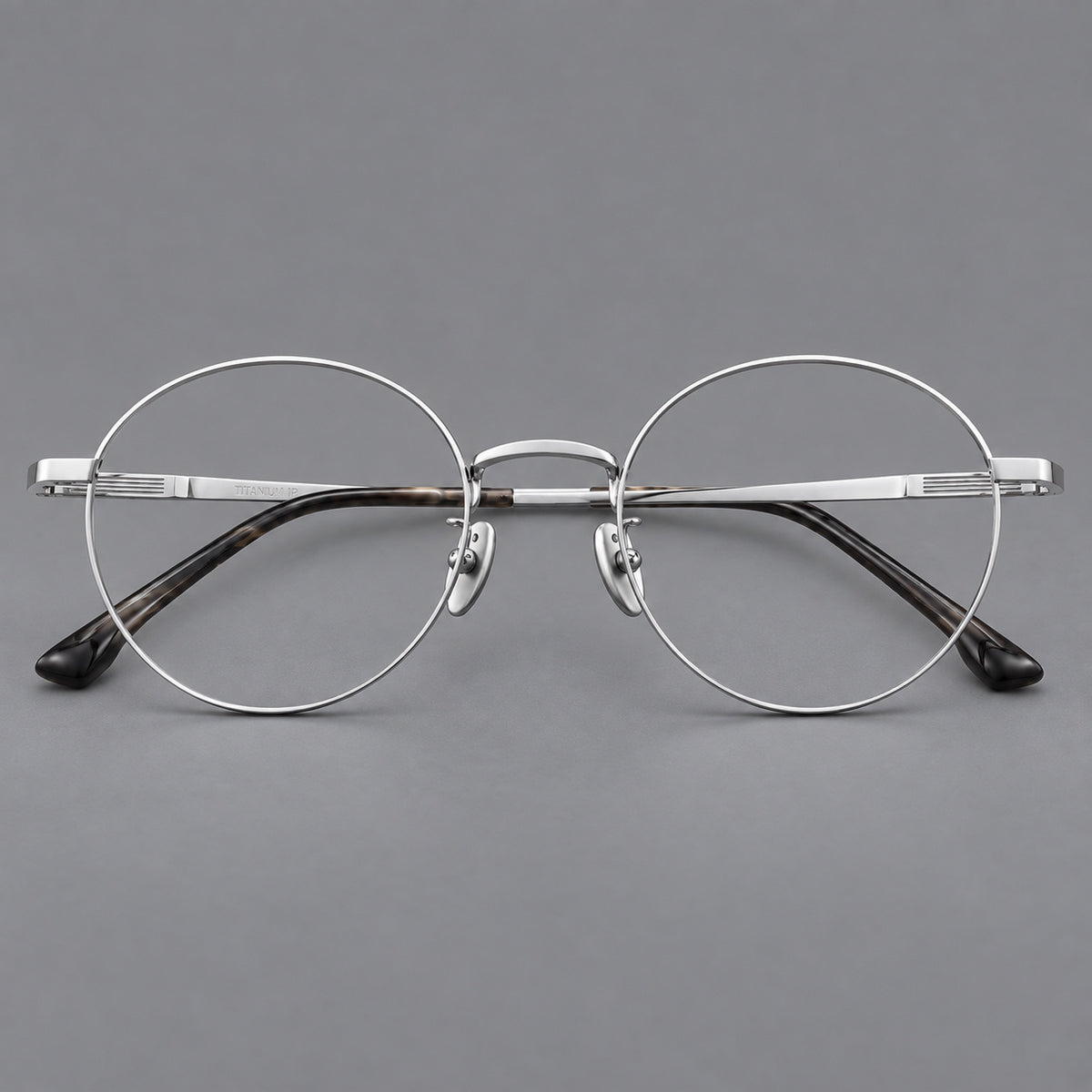 Classic circular titanium glasses with a raised bridge and lined temple accents in Silver, front view