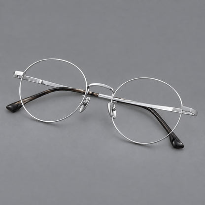 Classic circular titanium glasses with a raised bridge and lined temple accents in Silver, three quarter view lens detail