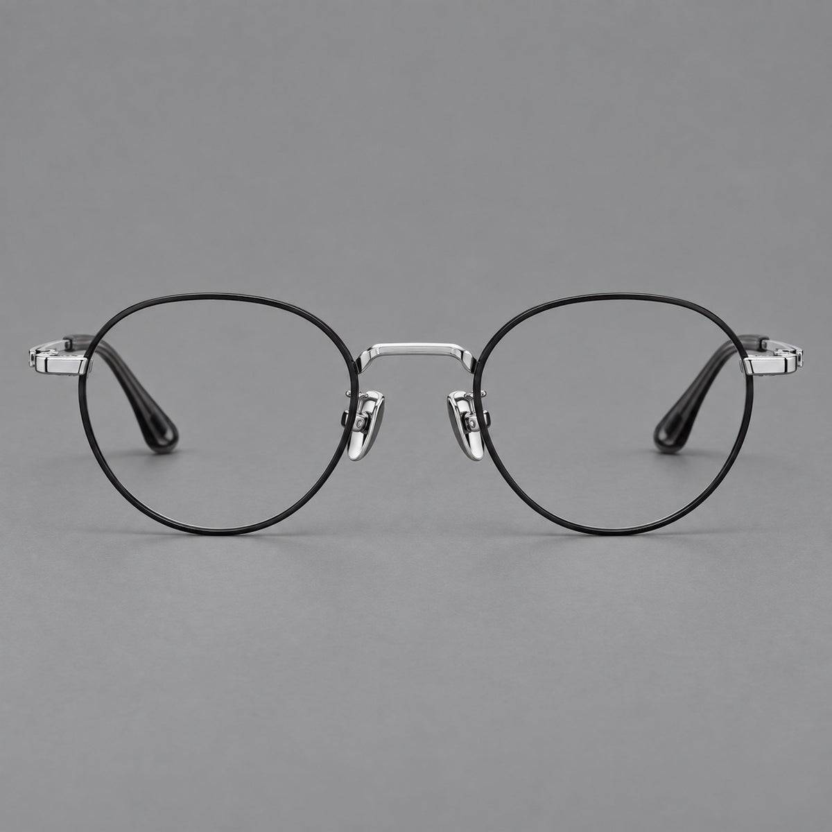 Small panto titanium glasses with an angular bridge and recessed temple details in Black and Silver, front view