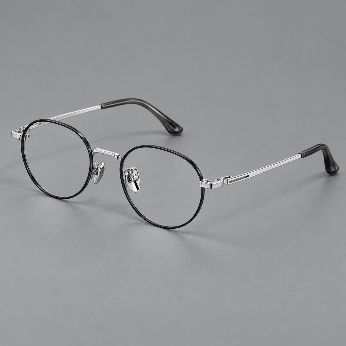 Small panto titanium glasses with an angular bridge and recessed temple details in Black and Silver, three quarter view