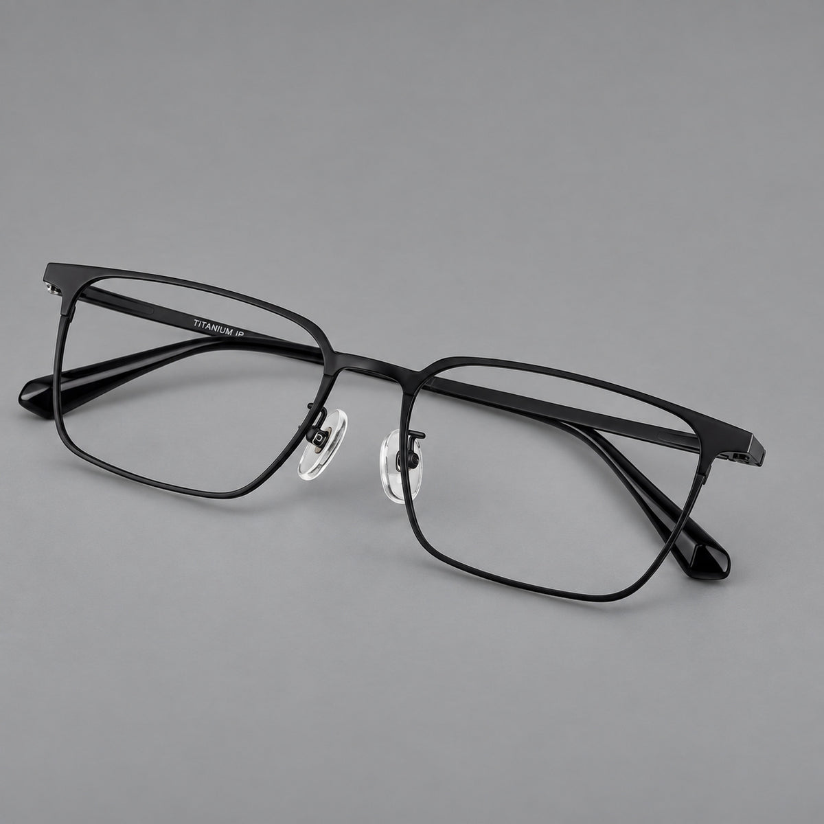 Bold rectangular titanium glasses with strong upper corners and flat metal temples in Black, three quarter view