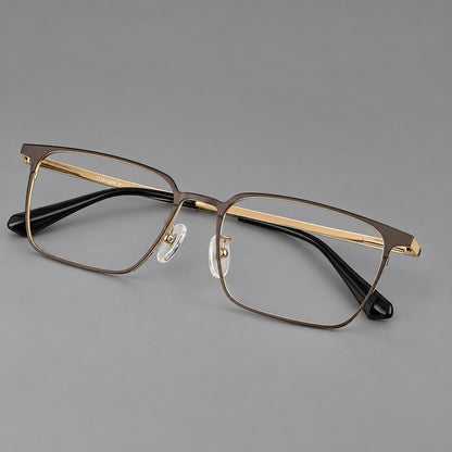 Bold rectangular titanium glasses with strong upper corners and flat metal temples in Gold, three quarter view lens detail