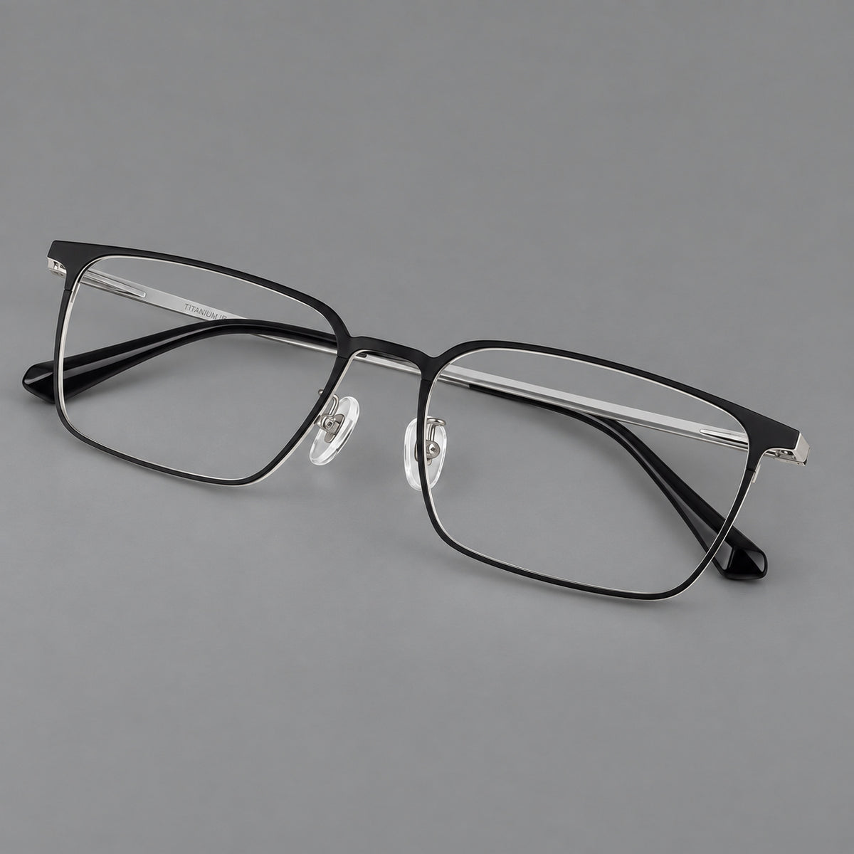 Bold rectangular titanium glasses with strong upper corners and flat metal temples in Black and Silver, three quarter view