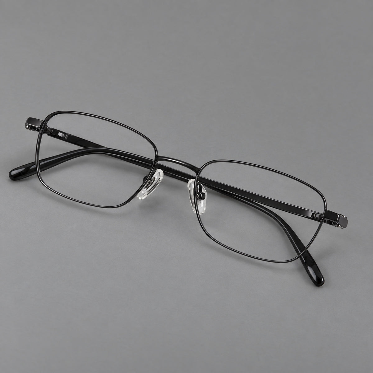 Shallow rectangular titanium glasses with a broad bridge and stepped temple joins in Black, three quarter view
