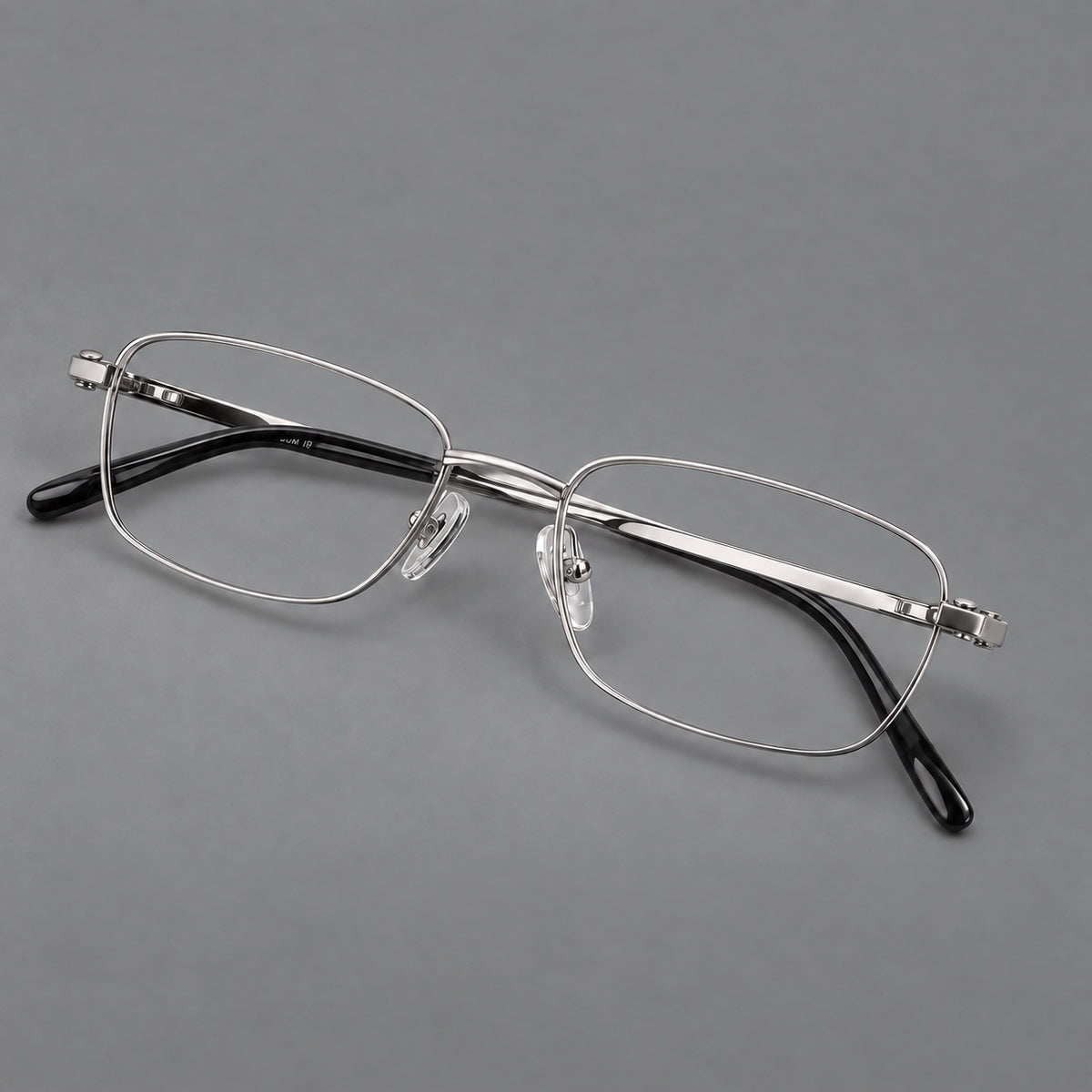 Shallow rectangular titanium glasses with a broad bridge and stepped temple joins in Silver, three quarter view